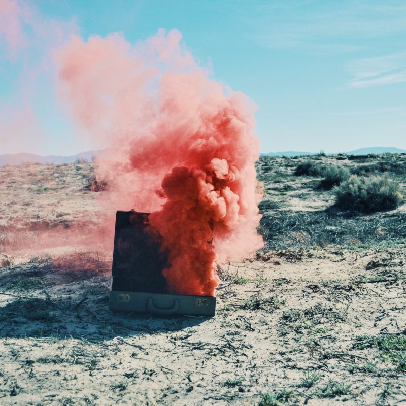 red smoke coming from an open briefcase on the beach