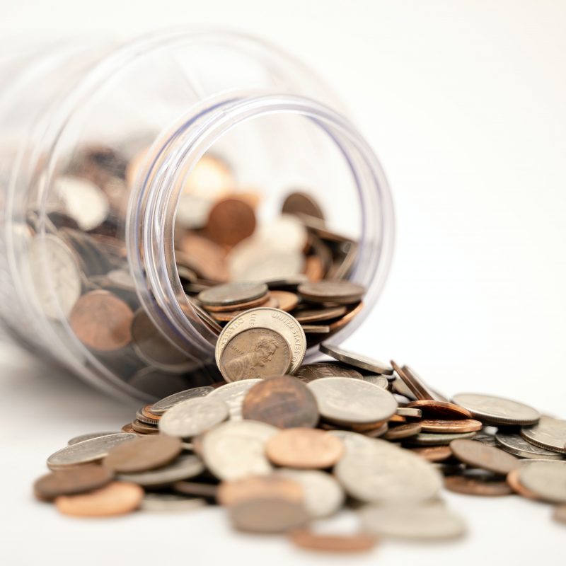 Money jar lying on side with money falling out