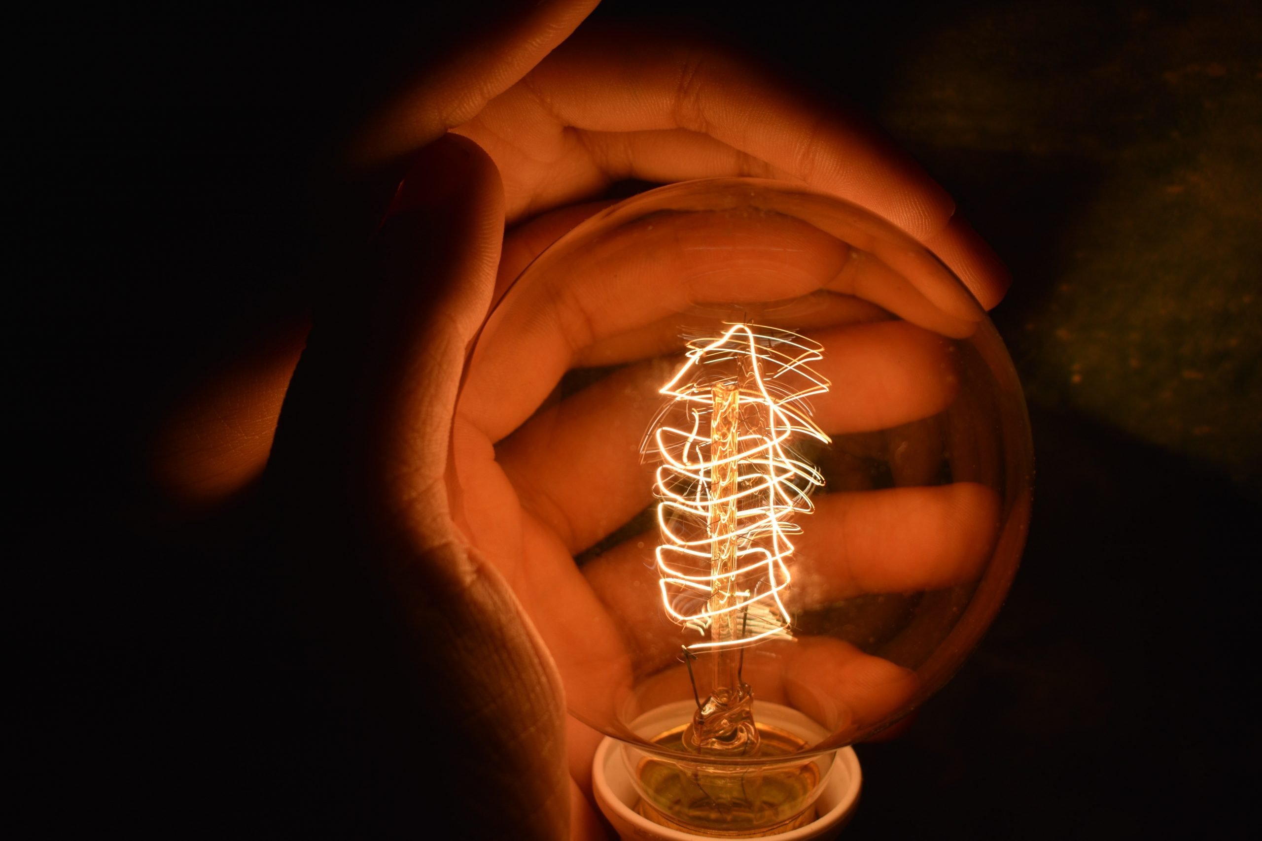 hands wrapped around a light bulb